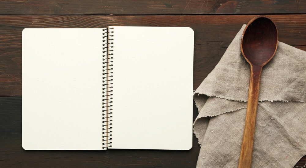 Das Bild "Die Löffelliste" zeigt ein leeres Notizheft mit einem Holzlöffel